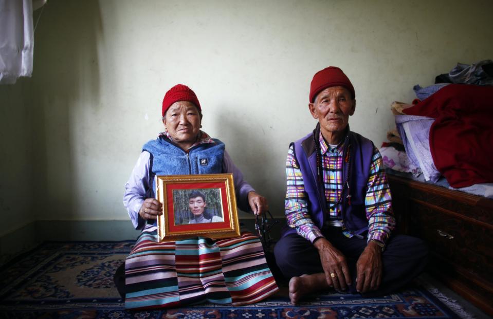 Nimdige Sherpa holds a portrait of her son Ang Kaji Sherpa, killed in an avalanche on Mount Everest, with her husband Ankchu Sherpa seated beside her in their rented apartment in Katmandu, Nepal, Wednesday, April 23, 2014. Dozens of Sherpa guides packed up their tents and left Mount Everest's base camp Wednesday, after the avalanche deaths of 16 of their colleagues exposed an undercurrent of resentment by Sherpas over their pay, treatment and benefits. (AP Photo/Niranjan Shrestha)