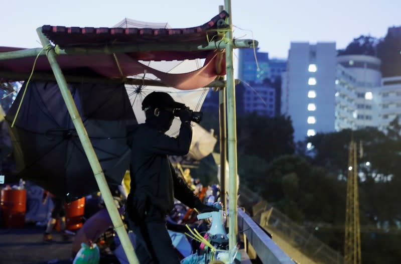 A protester looks through binoculars on barricade at the Chinese University in Hong Kong