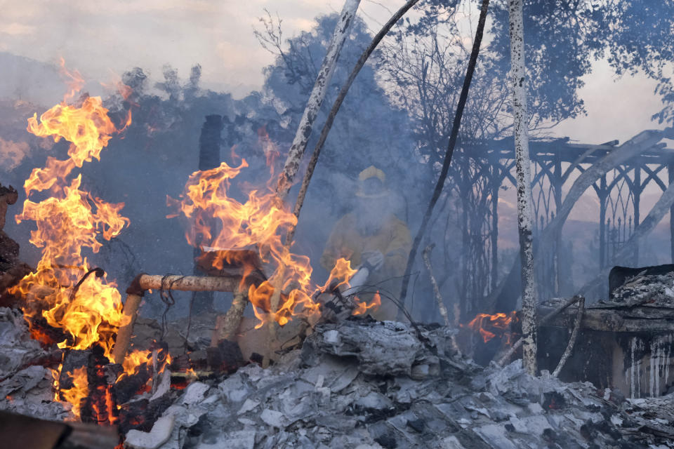 A firefighter tries to extinguish the flames at a burning house as the South Fire burns in Lytle Creek, San Bernardino County, north of Rialto, Calif., Wednesday, Aug. 25, 2021. (AP Photo/Ringo H.W. Chiu)