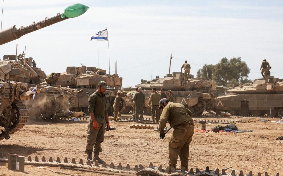 Israeli soldiers prepare their tanks at an army camp near the Gaza Strip border