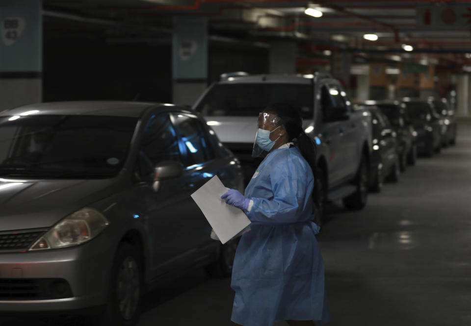 A health-care worker directs vehicles as patients queue for COVID-19 testing at a Dis-Chem drive-through testing station at the Table Bay Mall in Cape Town, South Africa, Friday, Jan. 8, 2021. South Africa with 60 million people has reported by far the most cases of the coronavirus in Africa, with more than 1.1 million confirmed infections. (AP Photo/Nardus Engelbrecht)