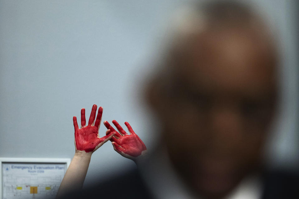 The stained hands of a demonstrator are held up behind Secretary of Defense Lloyd Austin protesting Israel's military action in Gaza, with U.S. weapons during a House Committee on Appropriations, Subcommittee on Defense budget hearing Fiscal Year 2025 on Capitol Hill, Wednesday, April 17, 2024 in Washington. (AP Photo/John McDonnell)