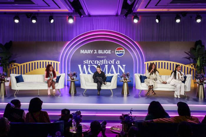 Four individuals seated on stage in an event with a  'MARY J. BLIGE PRESENTS strength of a woman' backdrop