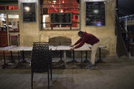 A waiter closes a bar terrace in Marseille, southern France, late Sunday Sept. 27, 2020. As restaurants and bars in Marseille prepared Sunday to shut down for a week as part of scattered new French coronavirus restrictions, Health Minister Olivier Veran insisted that the country plans no fresh lockdowns. (AP Photo/Daniel Cole)