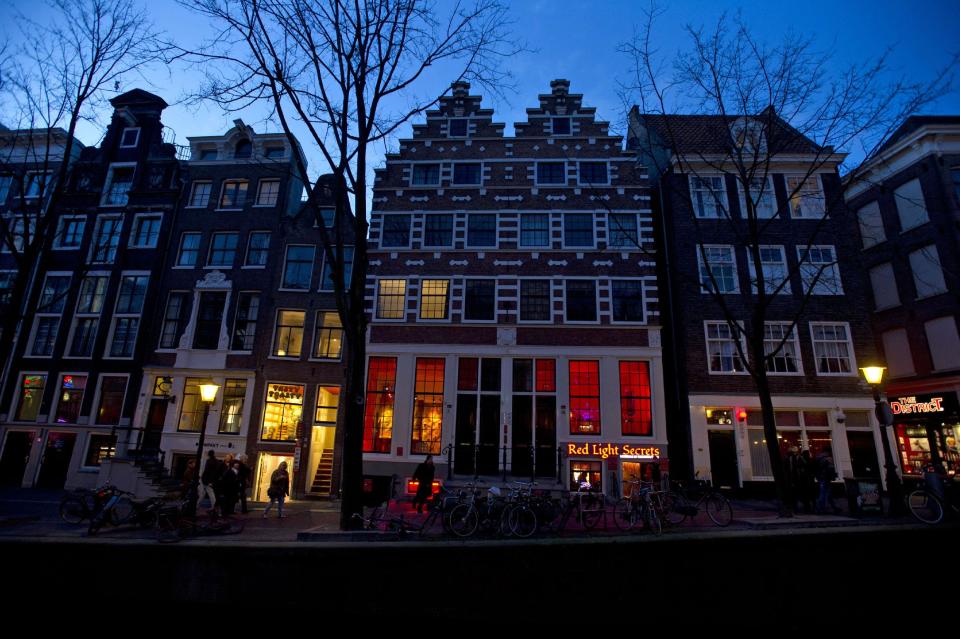 In this photo taken Tuesday, Feb. 4, 2014, the entrance of the 'Red Light Secrets' prostitution museum is seen, center, in Amsterdam. On any given evening, thousands of tourists stroll down the narrow streets of Amsterdam's famed Red Light District, gawking at ladies in lingerie who work behind windows, making a living selling sex for money. Now a small educational museum is opening in heart of the district that aims to show reality from the other side of the glass. Organizer Melcher de Wind says the Red Light Secrets museum is for those who want to learn more about how the area works without actually visiting a prostitute. (AP Photo/Evert Elzinga)