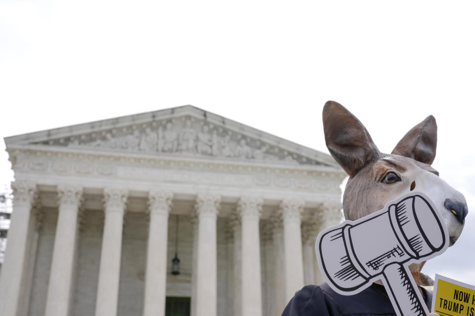 A demonstrator stands outside the Supreme Court as the justices prepare to hear arguments over whether Donald Trump is immune from prosecution in a case charging him with plotting to overturn the results of the 2020 presidential election, on Capitol Hill Thursday, April 25, 2024, in Washington. (AP Photo/Mariam Zuhaib)