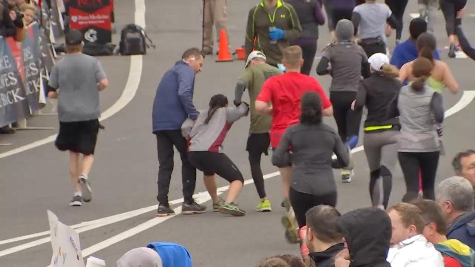 The woman is helped towards the finish line during the Philadelphia Love Run Half-Marathon