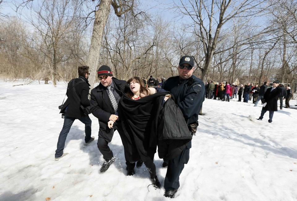 A protester is taken away by police and security during a campaign stop by Liberal leader Philippe Couillard in Montreal, Quebec April 4, 2014. Painted on their bodies were "I will remember" and " I remember Victoriaville" together with a red square. REUTERS/Christinne Muschi (CANADA - Tags: POLITICS CIVIL UNREST)