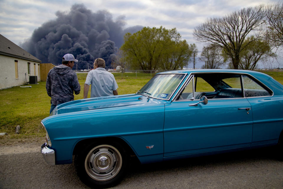 Ray Moore and Milton Perio observe the fire consuming TPC Group plant on Wednesday, Nov. 27, 2019, in Port Neches, Texas. Two massive explosions 13 hours apart tore through the chemical plant Wednesday, and one left several workers injured. (Marie D. De Jesús/Houston Chronicle via AP)