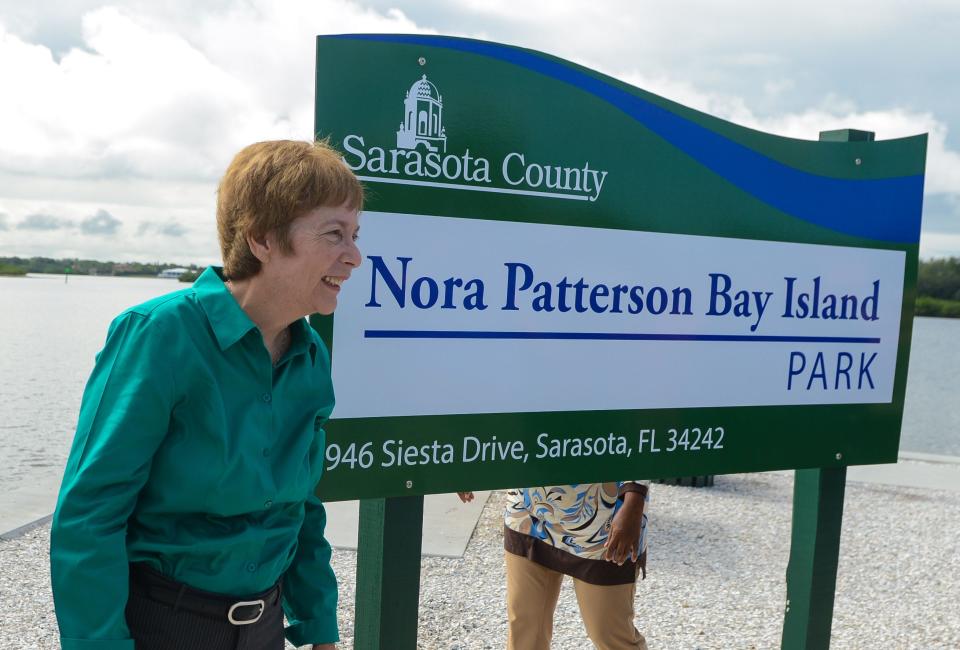 Nora Patterson stands next to the sign proclaiming the name change for Nora Patterson Bay Island Park at the 2015 renaming ceremony, when park improvements ranging from a new sea wall to new benches, fishing rails and signage were also unveiled.