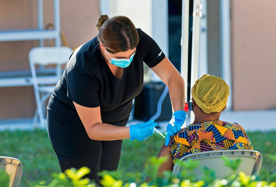 A health care worker administers a COVID-19 vaccine to a woman at a pop-up vaccination site at the United Haitian Baptist Church in West Palm Beach, Fla., on April 8.