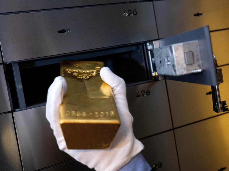 A man places a gold bar in a locker in a vault at the precious metals dealer Pro Aurum.