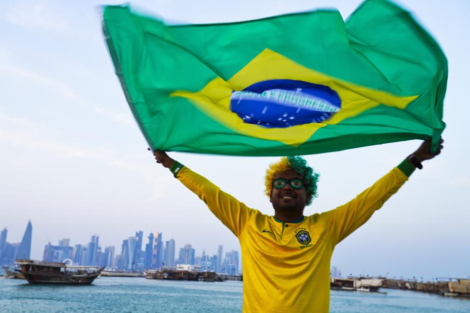 Brazil fan Ajmal Pial, of Khulna, Bangladesh, waves the Brazilian flag in Doha, Qatar, Friday, Nov. 18, 2022. Fans poured into Qatar on Friday ahead of the Middle East's first World Cup as Doha ordered beers not to be poured out at stadiums during the tournament — a last-minute surprise largely welcomed by the country's conservative Muslims and shrugged off by giddy fans. (AP Photo/Jon Gambrell)