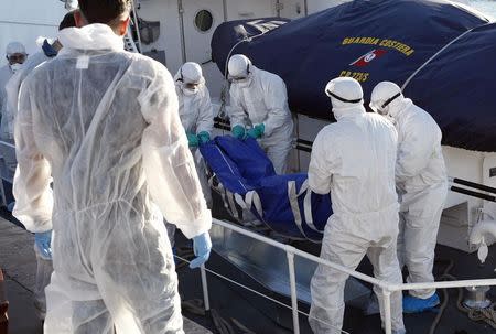 Health workers carry the dead body of a migrant, off a navy ship at the Sicilian harbour of Empedocle December 5, 2014. REUTERS/Antonio Parrinello