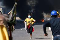 Demonstrators run after they set fire during the ongoing anti-government protests in Baghdad