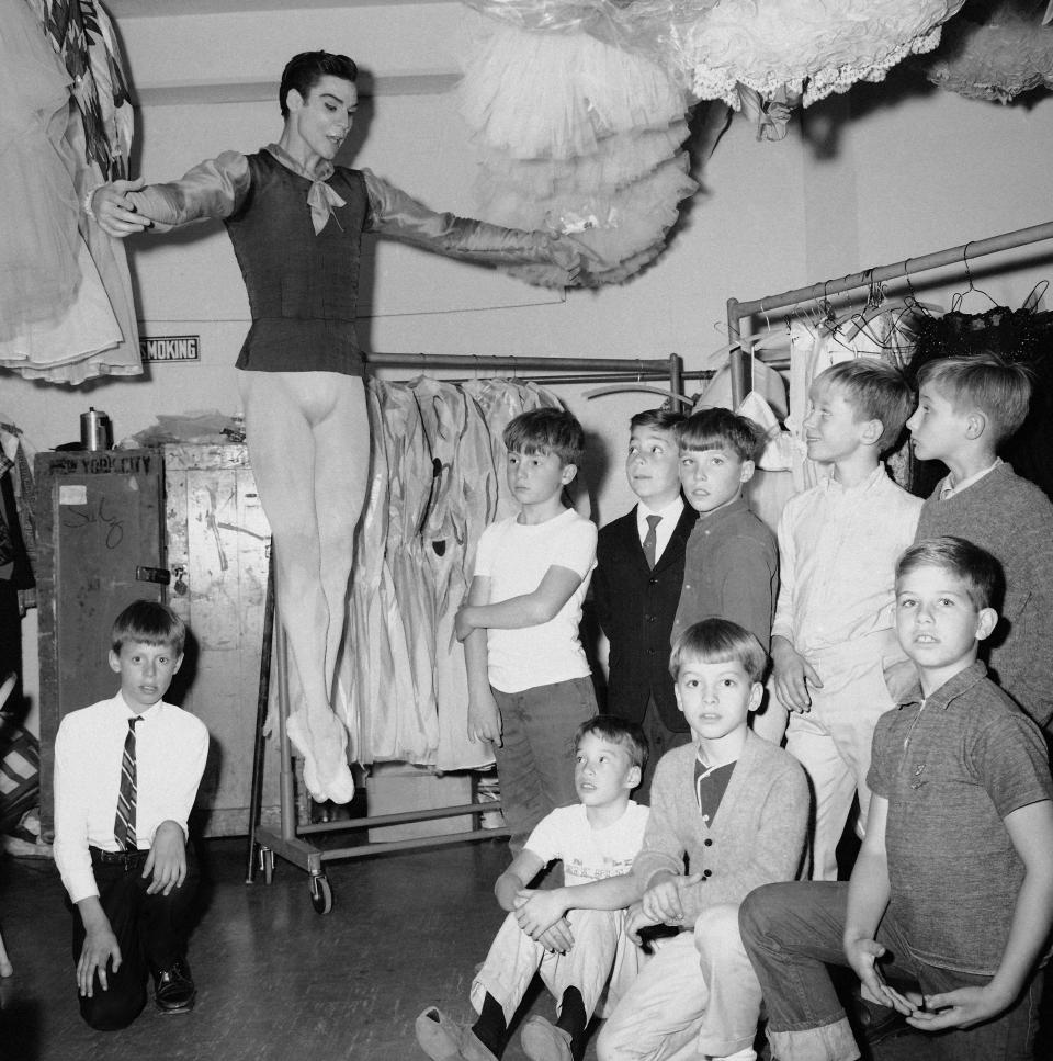 FILE - Jacques d'Amboise, principal dancer of the New York City ballet, demonstrates a jump to his young students backstage at New York's Lincoln Center on Oct. 30, 1965. D'Amboise, who grew up on the streets of upper Manhattan to become one of the world's premier classical dancers at New York City Ballet and spent the last four and a half decades providing free dance classes to city youth at his National Dance Institute, died Sunday, May 2, 2021. He was 86. His death was confirmed by Ellen Weinstein, director of the institute. (AP Photo, File)