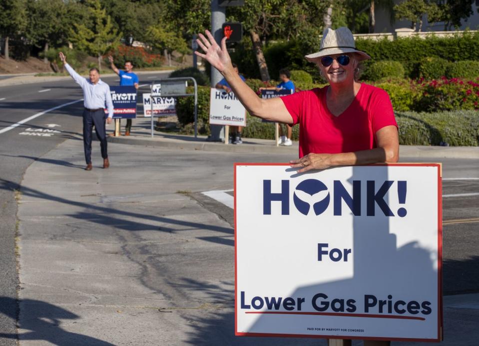 A woman holds a sign and waves.