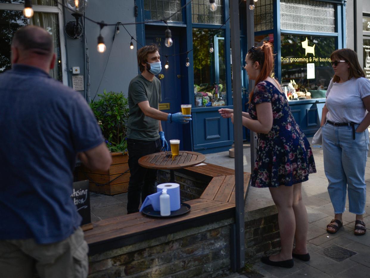 People are seen buying takeaway pints at a pub on Wandsworth Common, southwest London, in summer (Getty)
