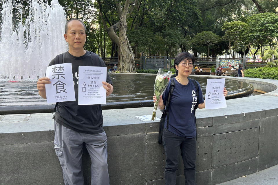 On the eve of the 34th anniversary of China's Tiananmen Square crackdown, Tiananmen activists Kwan Chun-pong, left and Lau Ka-yee at right hold up papers with the word Fasting and details of their plan to fast for about a day at the entrance of Hong Kong's Victoria Park as part of their commemoration on Saturday, June 3, 2023. The pair were taken away shortly by the police. (AP Photo/Kanis Leung)