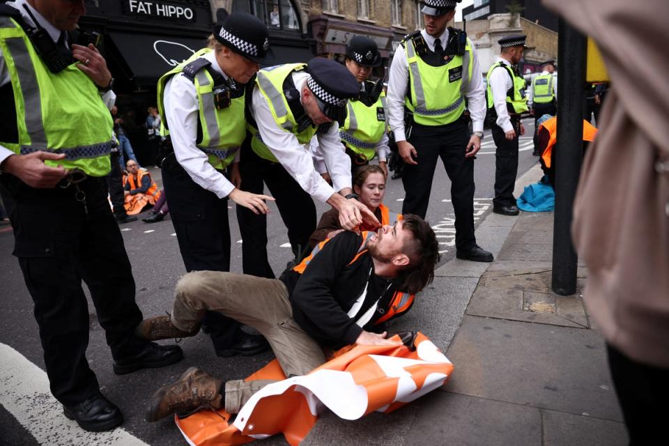 Police tackle an activist blocking the road in Shoreditch (Reuters)