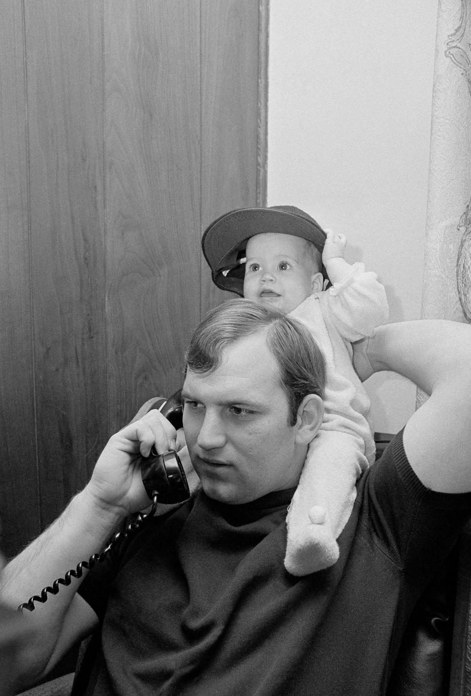 Thurman Munson holds his daughter Tracy Lynn, 7-months old, on his shoulders as he receives a telephone congratulations, Nov. 24, 1970, upon being named the American League Rookie of the Year. Munson is shown in his home in Canton.