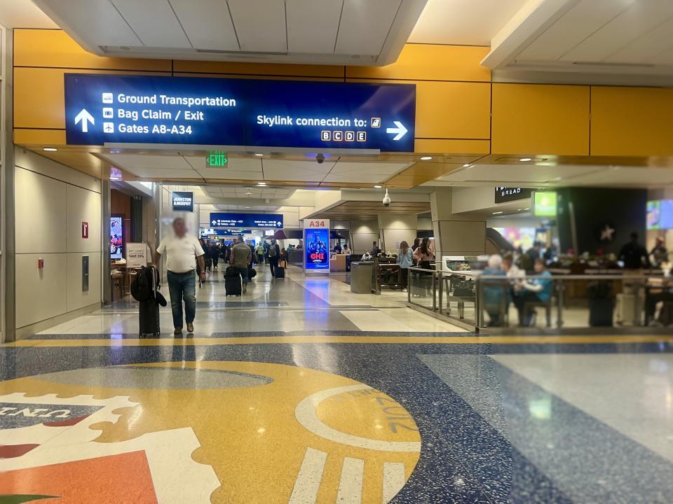 Man walking through DFW with black suitcase.