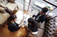 In this April 11, 2019, photo, Kenzo Watanabe, right top, and his fiancee Chiharu Yanagihara, center, check a tablet device showing catalog of wedding dresses with a staff at a Japanese wedding company in Tokyo. Japan is getting ready for its biggest celebration in years with the advent of the Reiwa era of soon-to-be emperor Naruhito. That means big opportunities for businesses hoping consumers will splash out on long holidays and memorabilia. (AP Photo/Eugene Hoshiko)