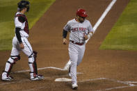 Cincinnati Reds' Eugenio Suarez (7) scores on a base hit by Tucker Barnhart during the 10th inning of a baseball game as Arizona Diamondbacks catcher Carson Kelly looks away, Friday, April 9, 2021, in Phoenix. (AP Photo/Matt York)