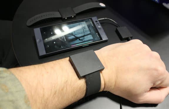 Basslet, its dongle connected to a smartphone, and another Basslet in the background.