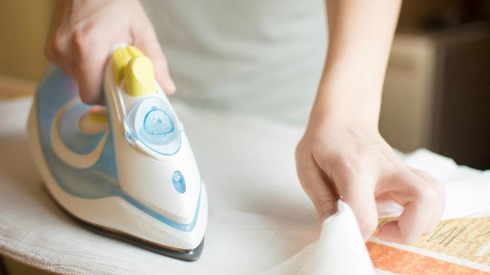 How to flatten a rug: Closeup image of woman hand ironing baby diapers with space for text