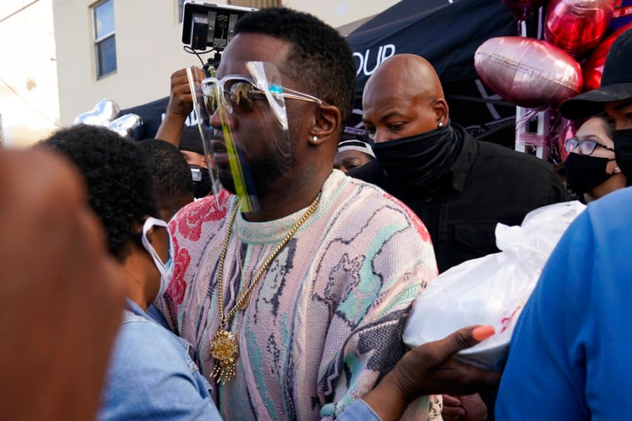 Rapper Sean “Diddy” Combs passes out fifty dollar bills to residents in the Overtown neighborhood of Miami, Tuesday, Dec. 29, 2020. Various organizations came together to also pass out gift cards and gift bags with essentials to those in need during the coronavirus pandemic. (AP Photo/Lynne Sladky)