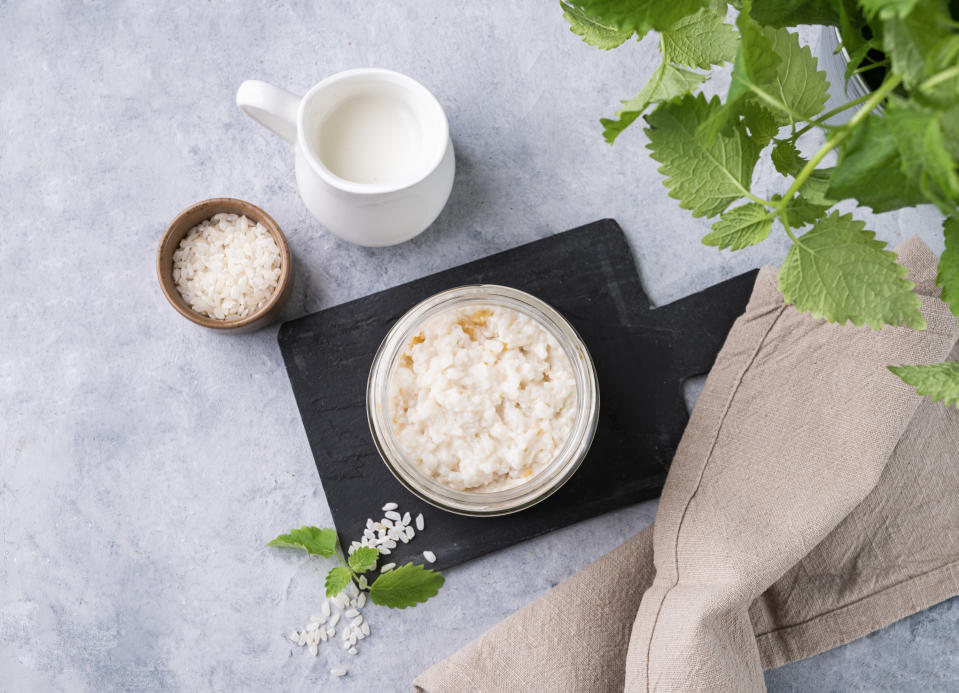 Rice that has an oatmeal like consistency in bowl on black wooden serving board.