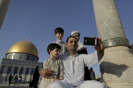 Palestinian Muntasser Ne'erat, 31, from the West Bank city of Nablus, takes a selfie photo with his children in front of the Dome of the Rock on the compound known to Muslims as Noble Sanctuary and to Jews as Temple Mount, in Jerusalem's Old City, during the holy month of Ramadan, July 1, 2015. This is Ne'erat's first visit to the compound. Palestinians young and old have jumped on a trend for taking "selfies" at Al Aqsa, the 8th century Muslim shrine in Jerusalem, both as a personal memento and for relatives prevented from or unable to visit the ancient compound. REUTERS/Ammar Awad