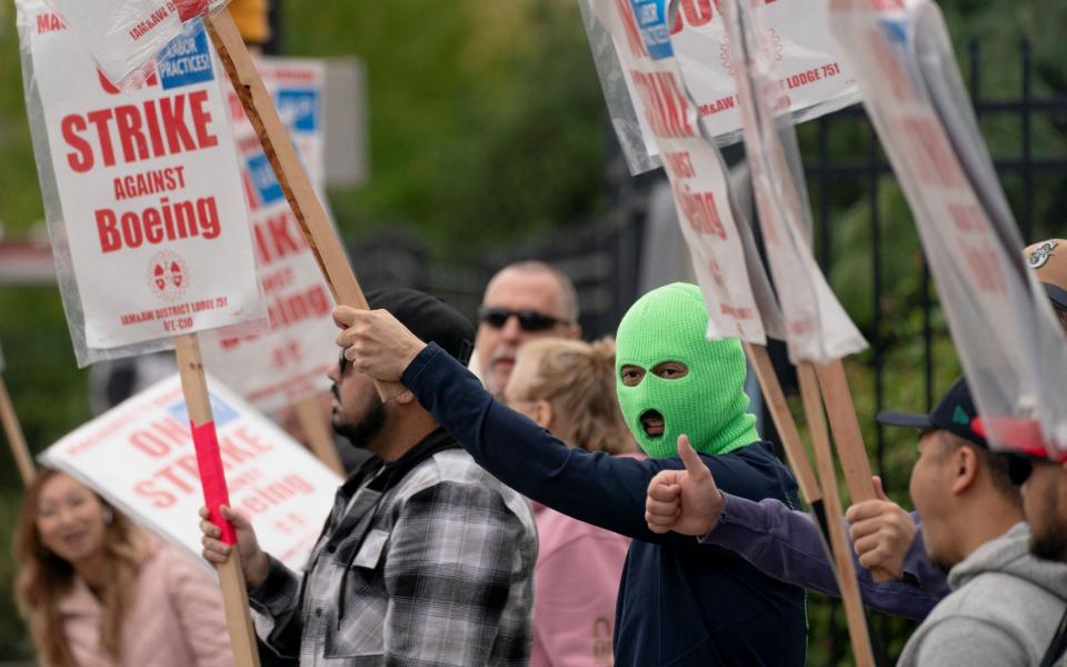 Boeing factory workers and supporters gather on a picket line during the third day of a strike near the entrance to a Boeing factory in Renton, Washington state, yesterday