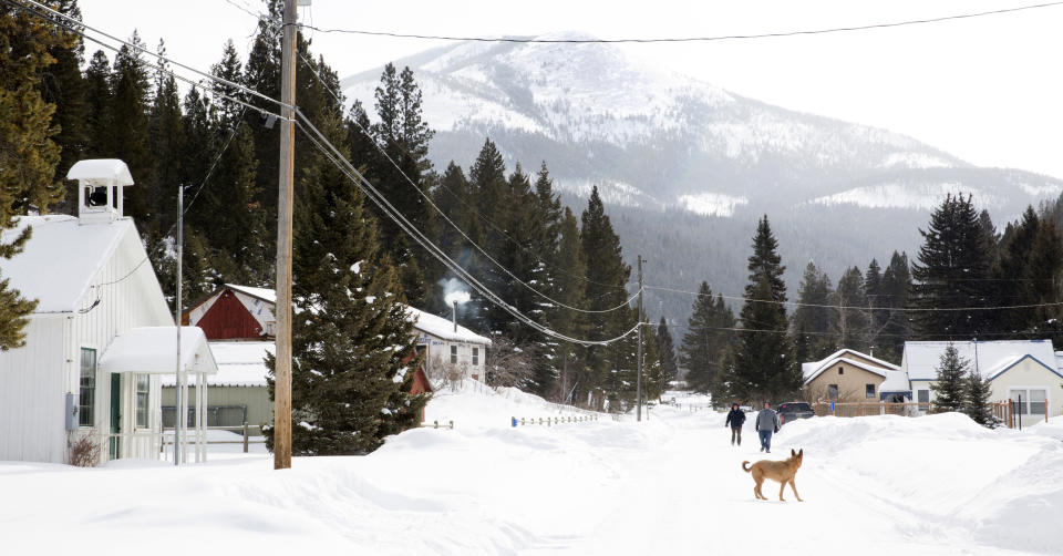 Pedestrians walk down a road in Rimini, Mont., on Feb. 18, 2019. The community was added to the Environmental Protection Agency's Superfund list in 1999. Contaminated soil in residents’ yards was replaced, and the EPA has provided bottled water for a decade. But polluted water still pours from the mines and into Upper Tenmile Creek. (AP Photo/Janie Osborne)