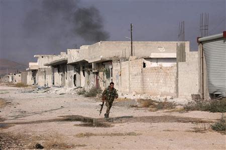 A Syrian army soldier loyal to Syria's President Bashar al-Assad carries his weapon as he runs along a street in the town of Safira November 1, 2013. REUTERS/George Ourfalian