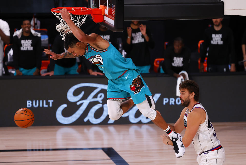 Brandon Clarke, left, of the Memphis Grizzlies' with a slam dunk over the Toronto Raptors during the second half of an NBA basketball game Sunday, Aug. 9, 2020, in Lake Buena Vista, Fla. (Kevin C. Cox/Pool Photo via AP)