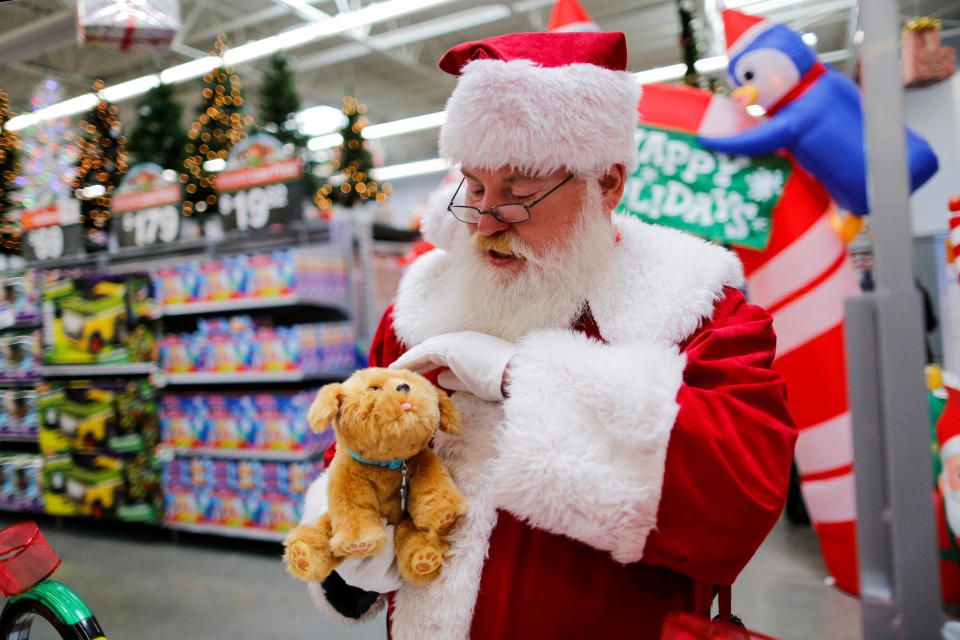 A man dressed as Santa Claus pets a toy as products are display for Christmas season at a Walmart store in Teterboro, New Jersey, U.S., October 26, 2016. REUTERS/Eduardo Munoz