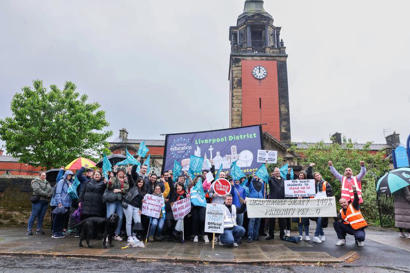 A picket line outside The Blue Coat School in Liverpool - a number of teachers hold banners and flags