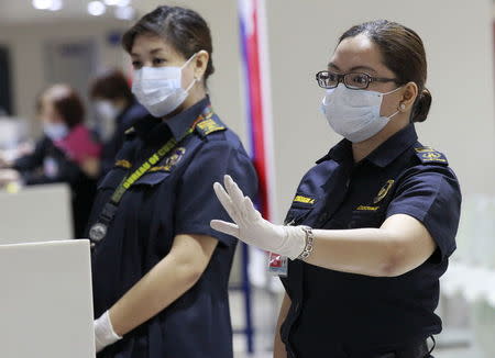 A customs inspector wearing a face mask gestures as she waits for flight passengers arriving from South Korea at the arrival area of Ninoy Aquino International Airport in Manila, June 9, 2015. REUTERS/Romeo Ranoco