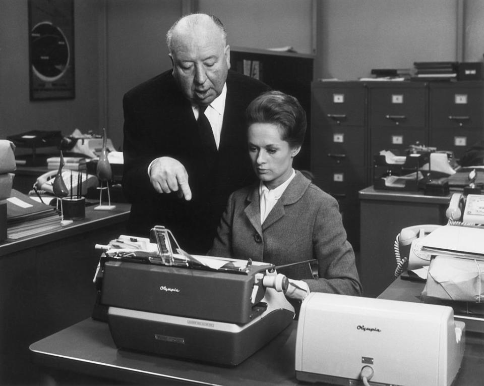 Hitchcock standing behind Hedren, who's at a typewriter