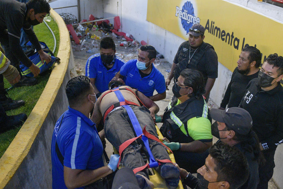 An injured man is evacuated after fans clashing during a Mexican soccer league match between the host Queretaro and Atlas from Guadalajara, at the Corregidora stadium, in Queretaro, Mexico, Saturday, March 5, 2022. (AP Photo/Sergio Gonzalez)