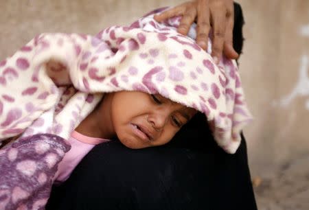 A displaced woman from Hodeidah city carries her sick daughter at a school where displaced people live, in Sanaa, Yemen June 22, 2018. REUTERS/Mohamed al-Sayaghi