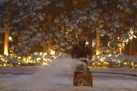 A man cleans the entry way of a building after a winter storm arrived in Washington January 22, 2016. REUTERS/Carlos Barria