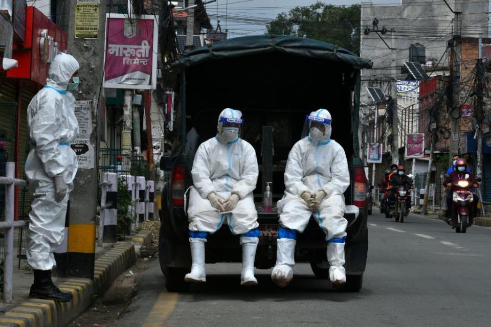 Nepal army wearing personal protective equipment (PPE) suits in a vehicle as they wait to transport the body of a person who died from Covid-19 coronavirus to a crematorium in Kathmandu.