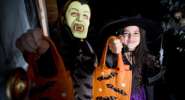 Children in costumes at a Hallowe'en party, holding orange party bags