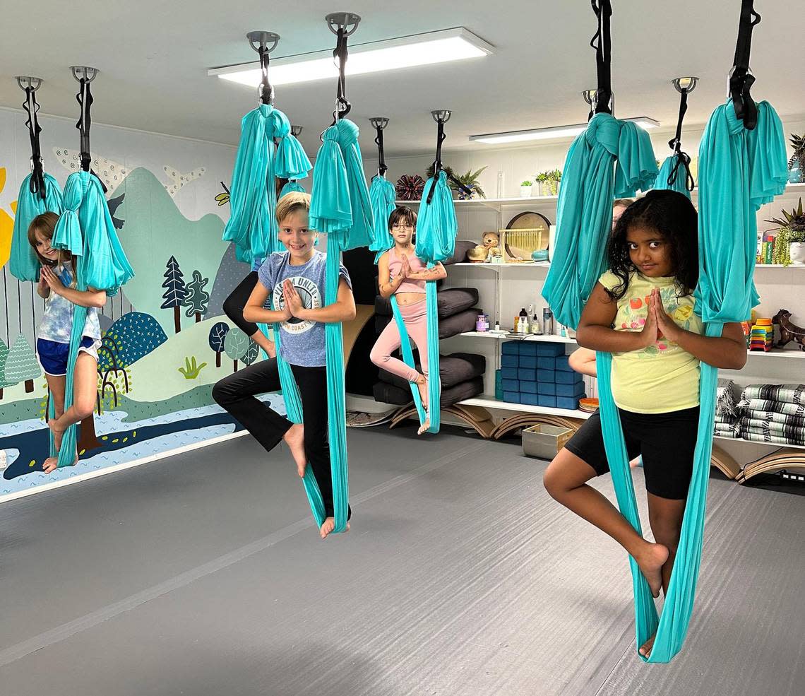 A group of children pose during an aerial yoga class at Nanda Yoga studio.