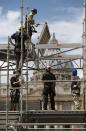 Construction workers set up scaffoldings in front of St. Peter's Basilica at the Vatican, Tuesday, April 22, 2014. The scaffoldings will be used by international media covering the canonization ceremony of two late popes; John Paul II and John XXIII, that will be held in St. Peter's Square on Sunday April 27, 2014. (AP Photo/Domenico Stinellis)