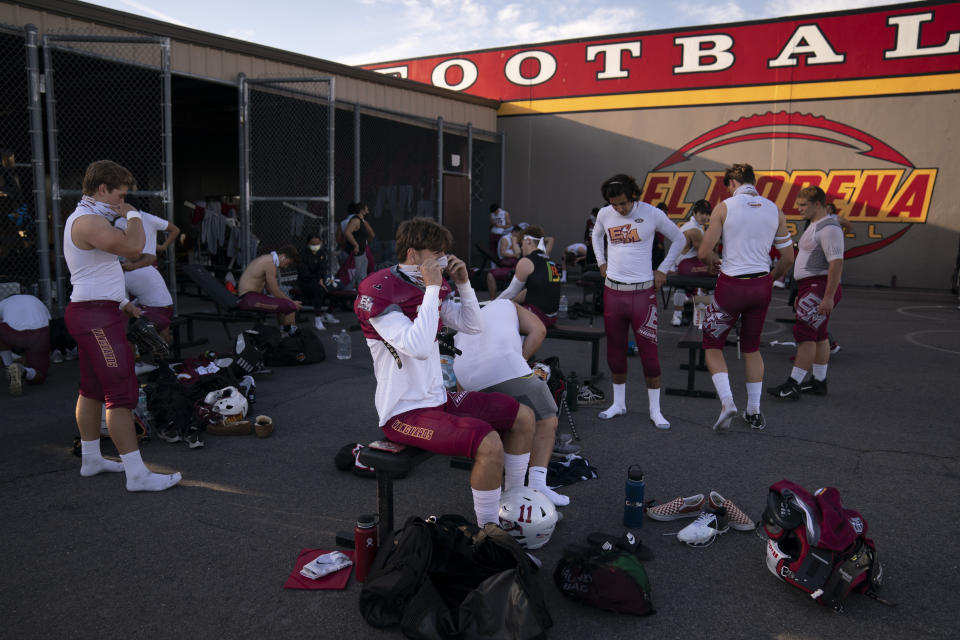 El Modena tight end Tom Leonard, center, and teammates put on their gear outdoors due to COVID-19 restrictions before the team's high school football game with El Dorado in Orange, Calif., Friday, March 19, 2021. The team recently played its first football game in a year as more California counties ease coronavirus restrictions and life in the nation’s most populous state inches back to normalcy. (AP Photo/Jae C. Hong)