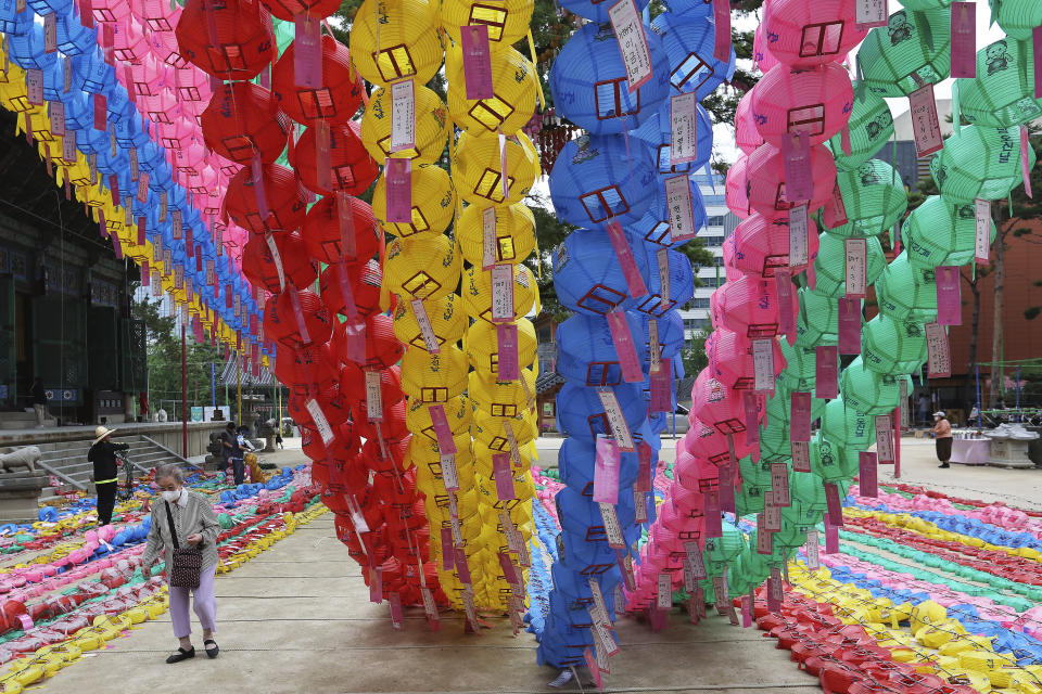 A woman wearing a face mask to help curb the spread of the coronavirus passes by lantern decorations for Buddha's birthday at the Chogyesa temple in Seoul, Monday, June 29, 2020. This year a ceremony to celebrate the birthday was put off from April 30 to May 30 due to the coronavirus. (AP Photo/Ahn Young-joon)